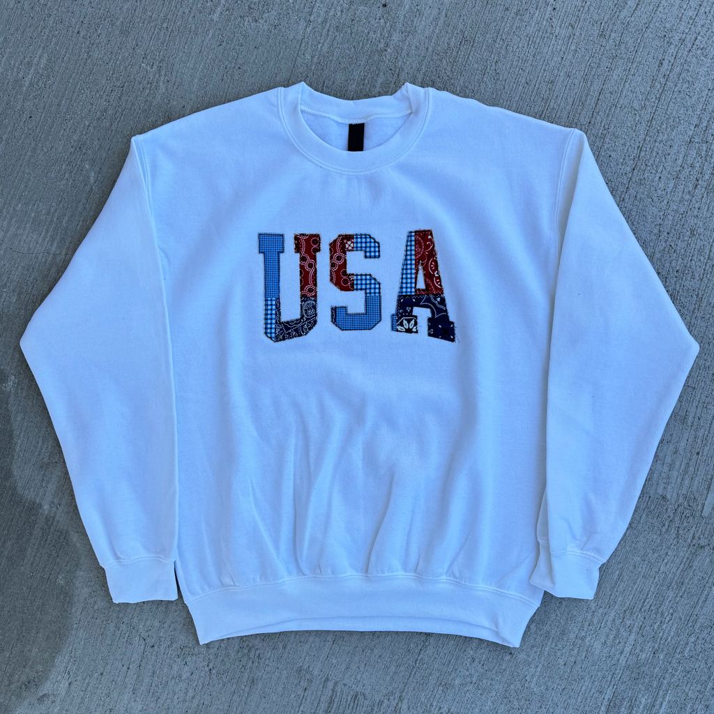 White sweatshirt with 'USA' patterned letters design on a gray surface