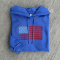 Blue hoodie with American flag design on a gray surface