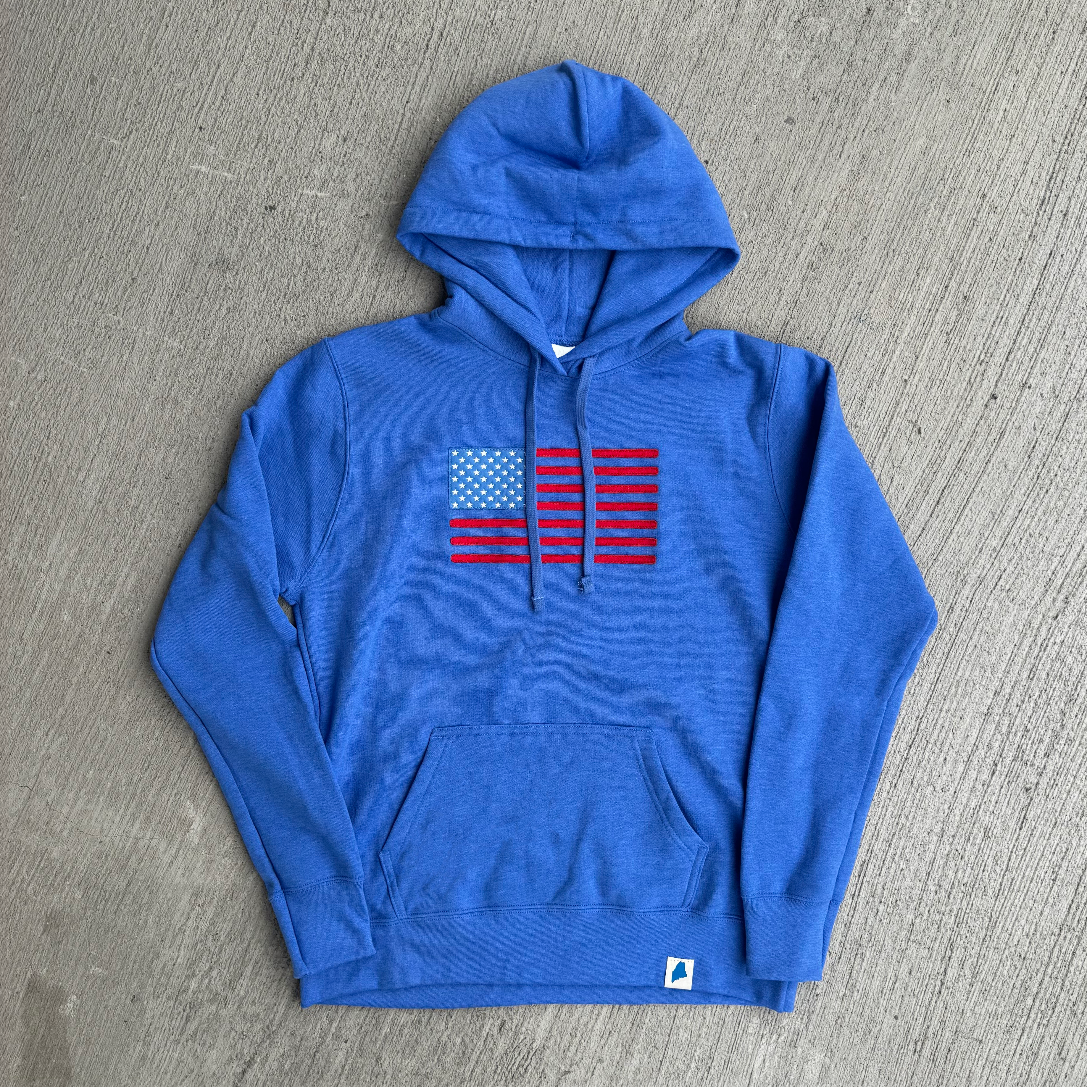Blue hoodie with American flag design on a gray surface
