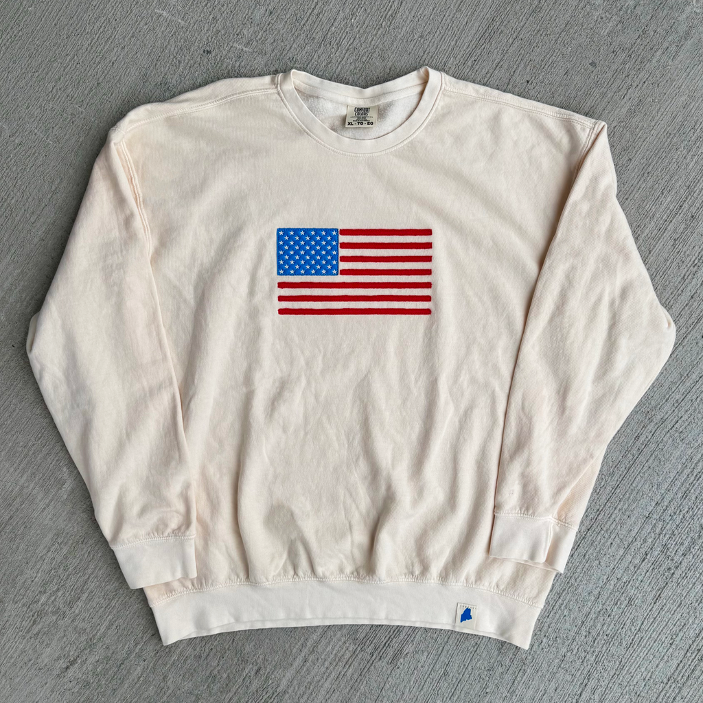 Off white sweatshirt with American flag design on a gray background