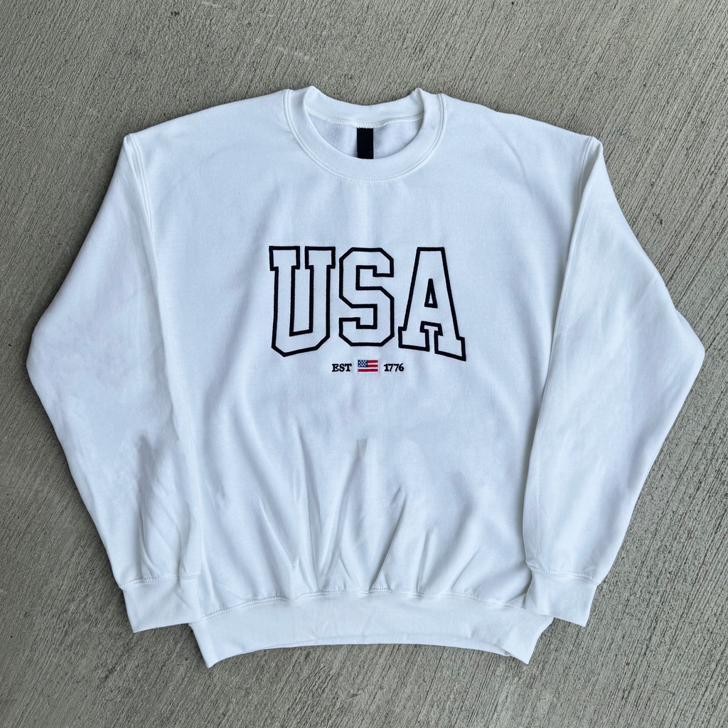 White sweatshirt with 'USA' text on a gray surface