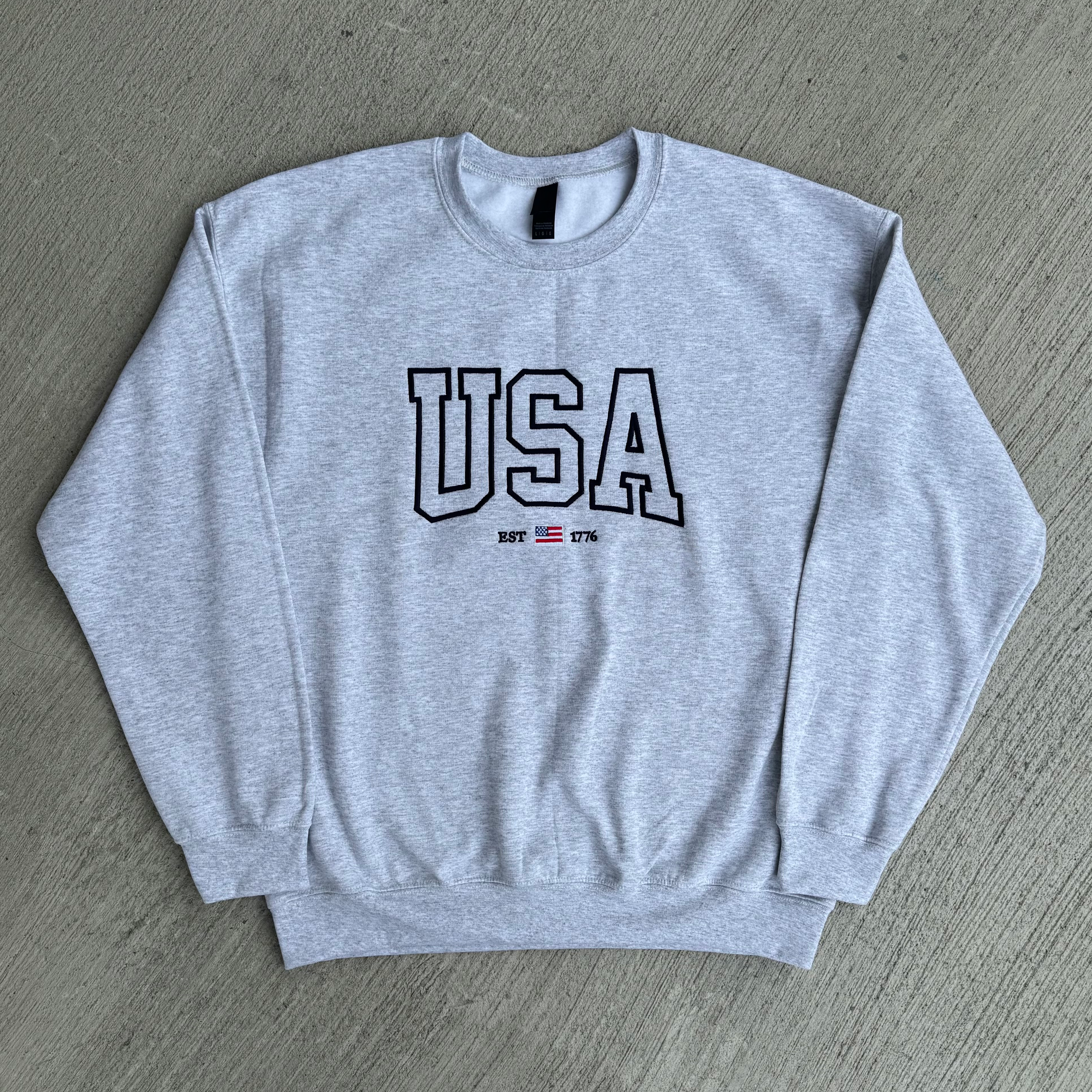 Gray sweatshirt with 'USA' text on a gray surface