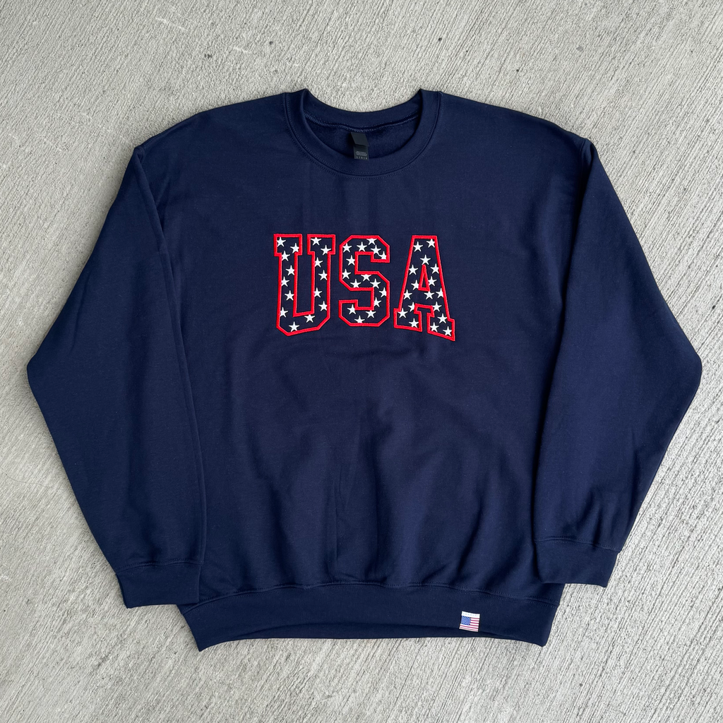 Navy blue sweatshirt with 'USA' text on a gray surface