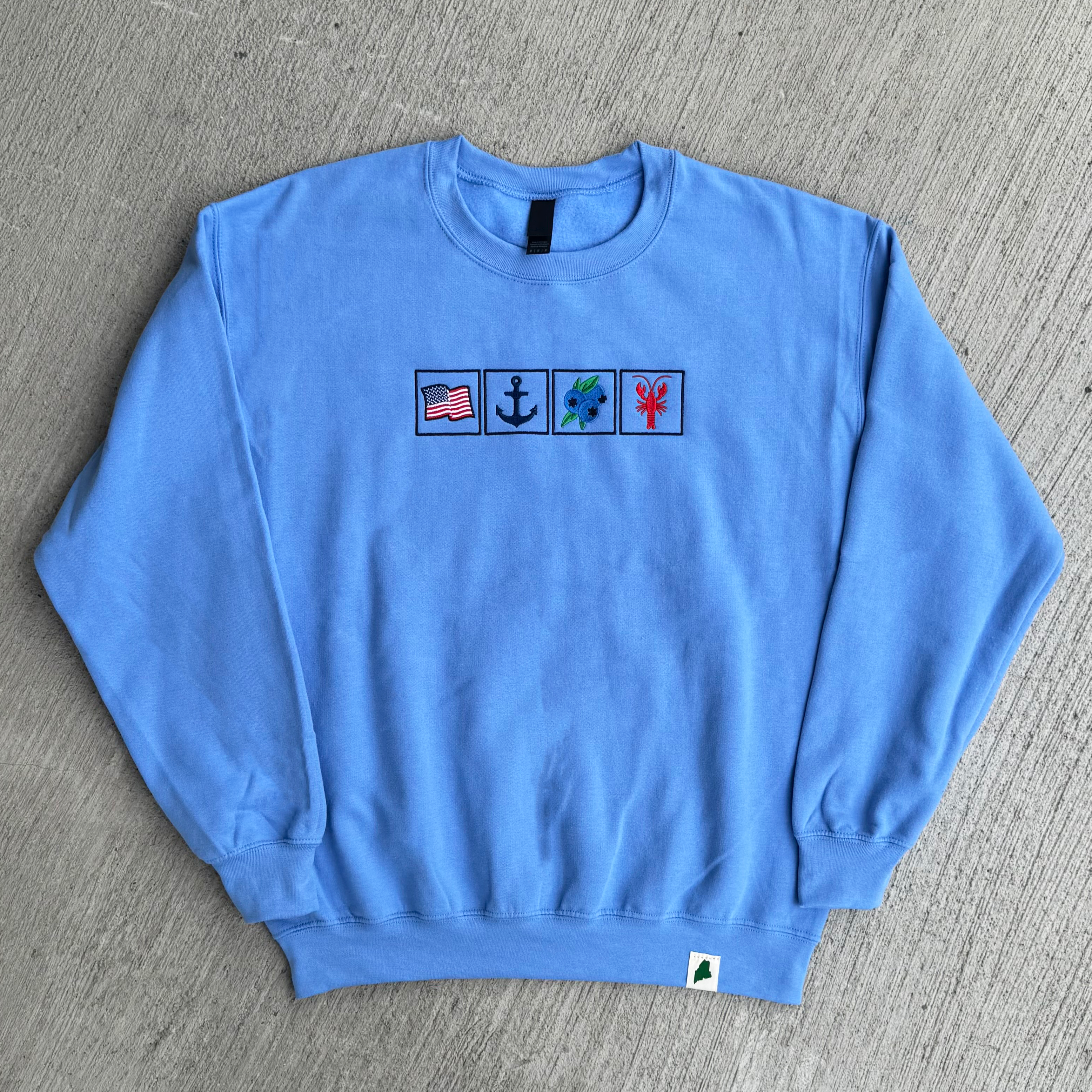 Blue sweatshirt with embroidered symbols on a gray surface