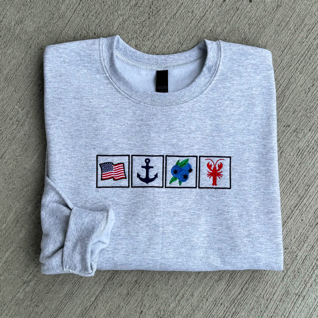 Folded gray sweatshirt with embroidered symbols on a gray surface