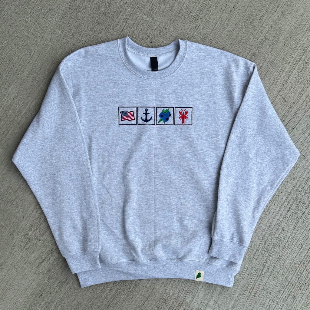 Gray sweatshirt with embroidered symbols on a gray surface