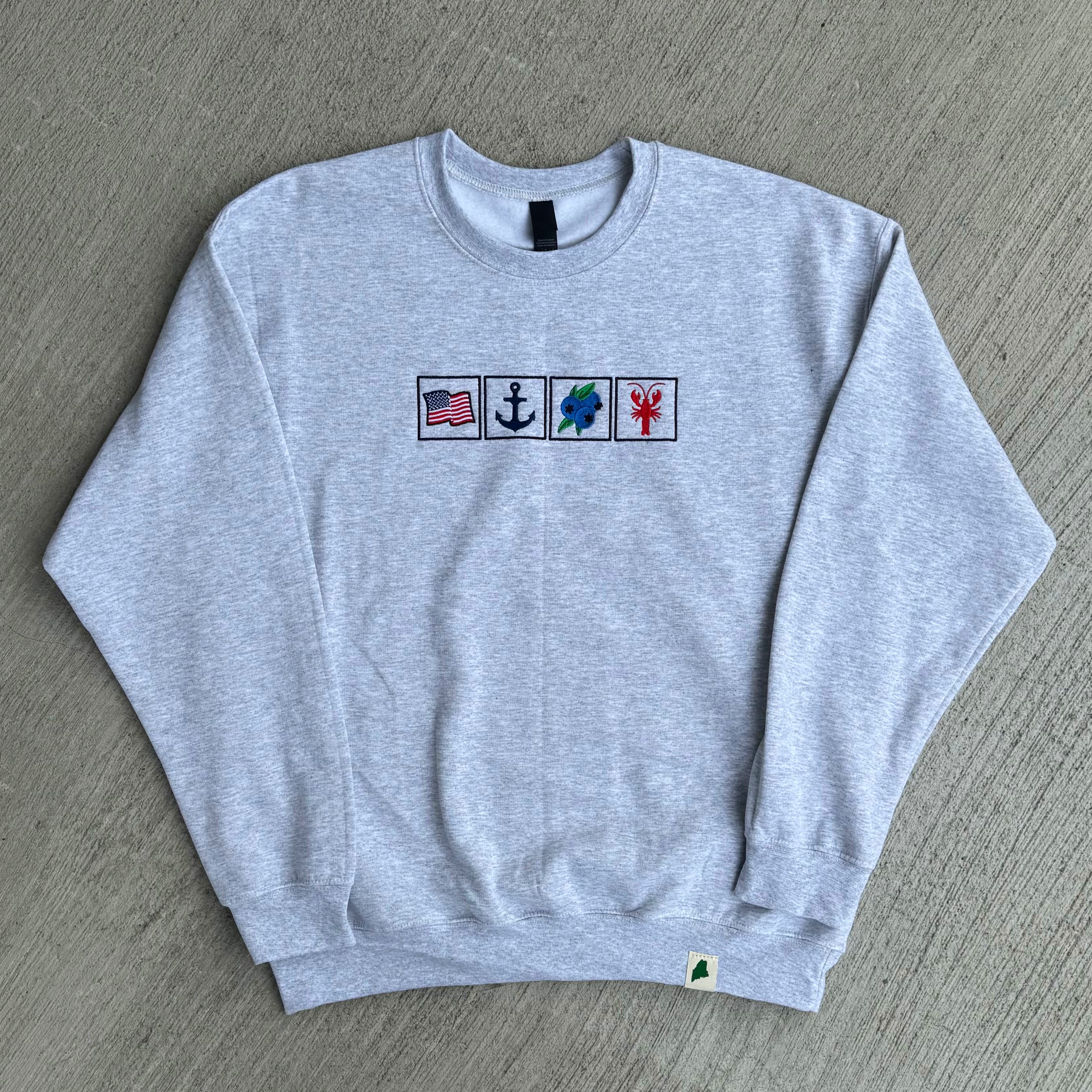 Gray sweatshirt with embroidered symbols on a gray surface