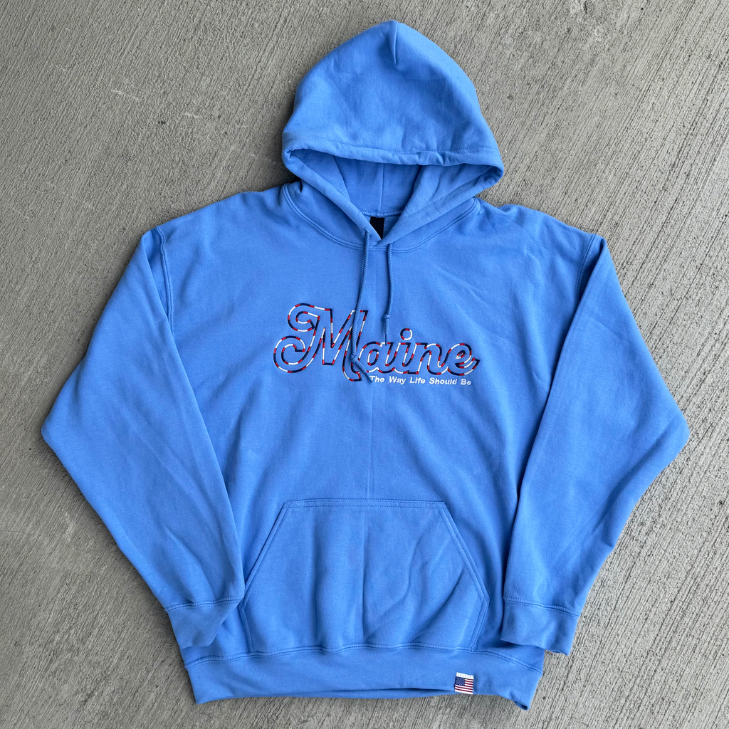 Blue hoodie with 'Maine The Way Life Should Be' text on a gray surface