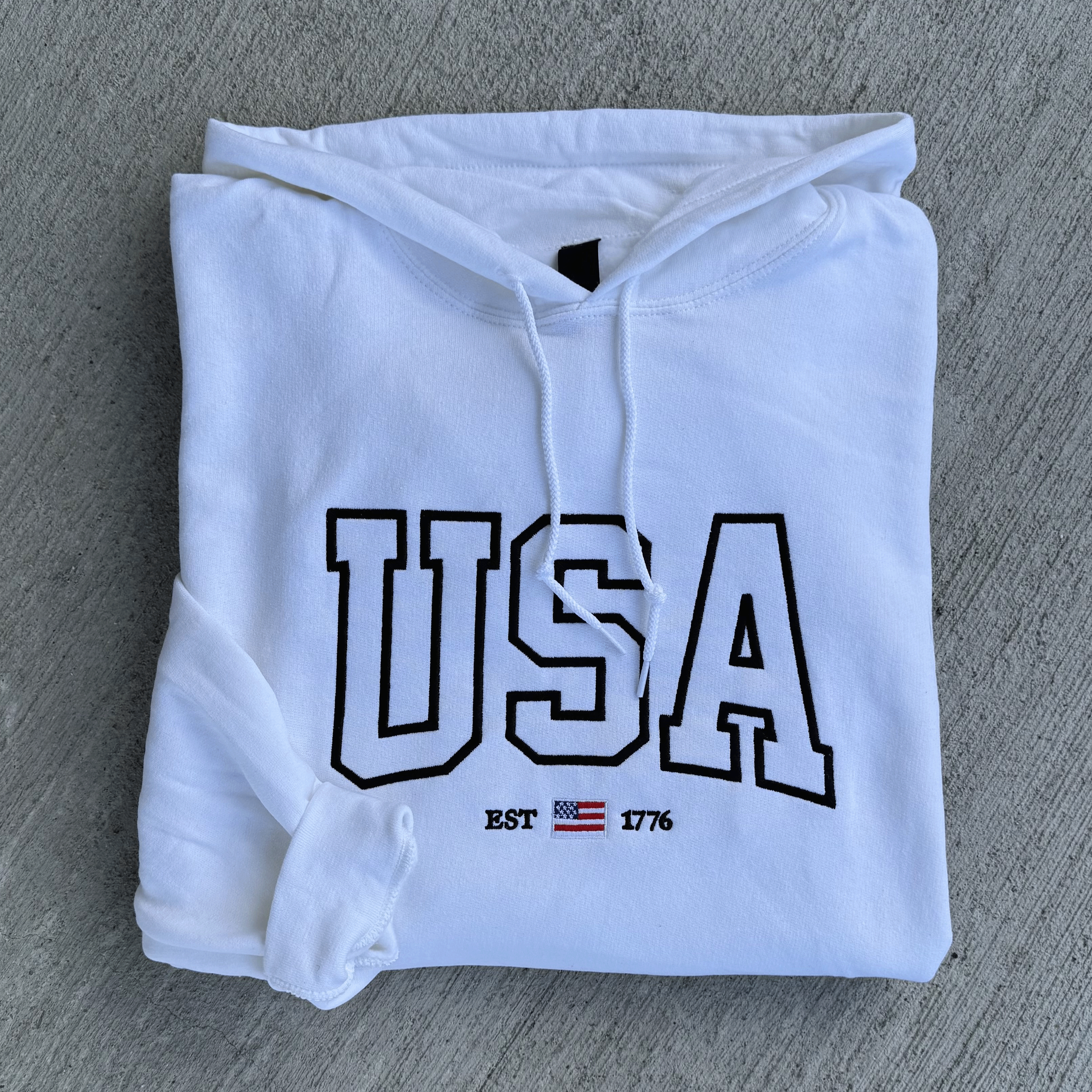 White hoodie with 'USA' text on a gray surface
