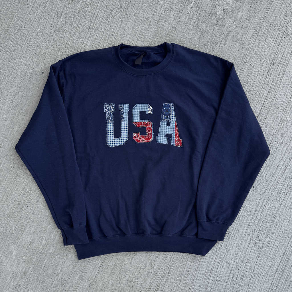 Navy blue sweatshirt with 'USA' print on a gray surface