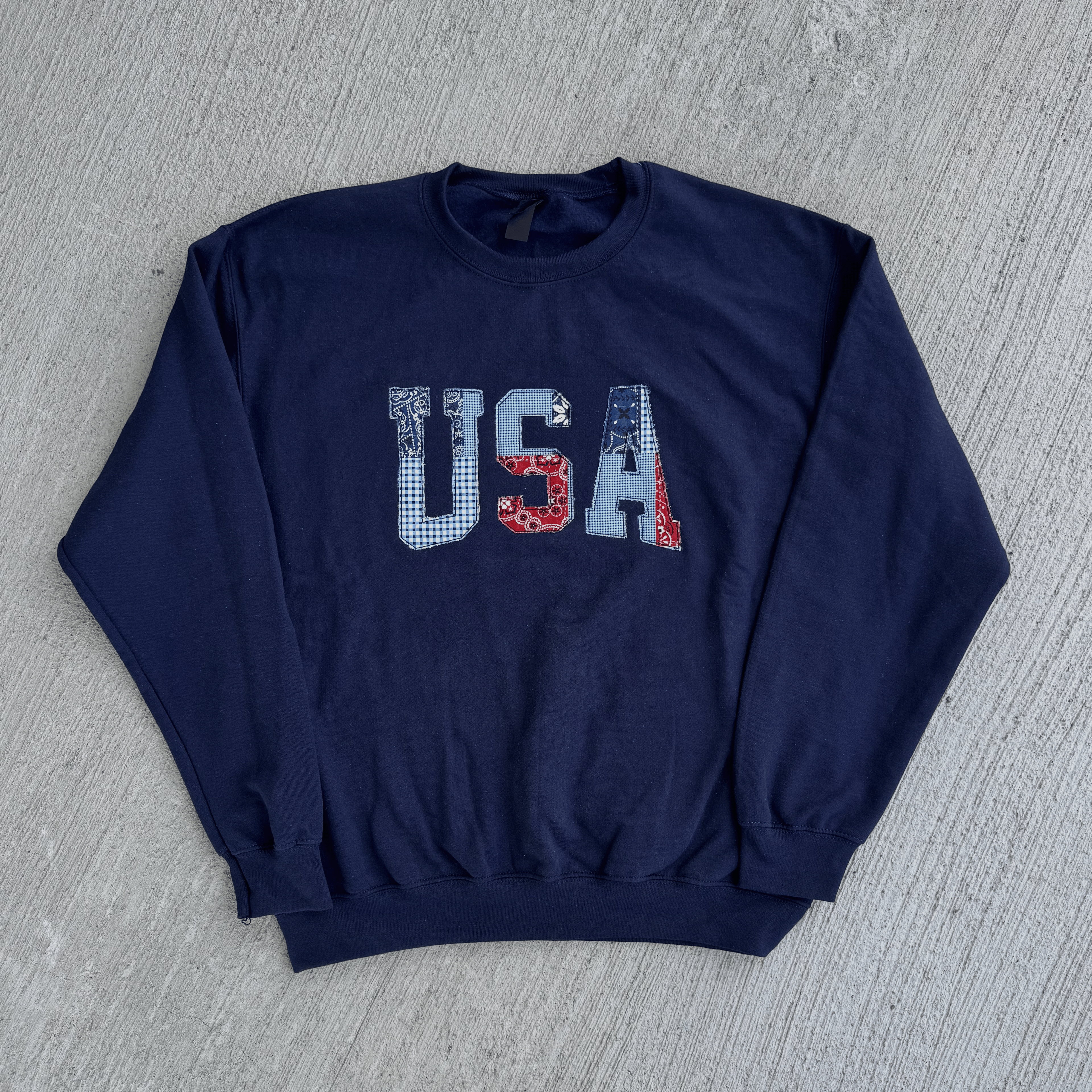 Navy blue sweatshirt with 'USA' print on a gray surface