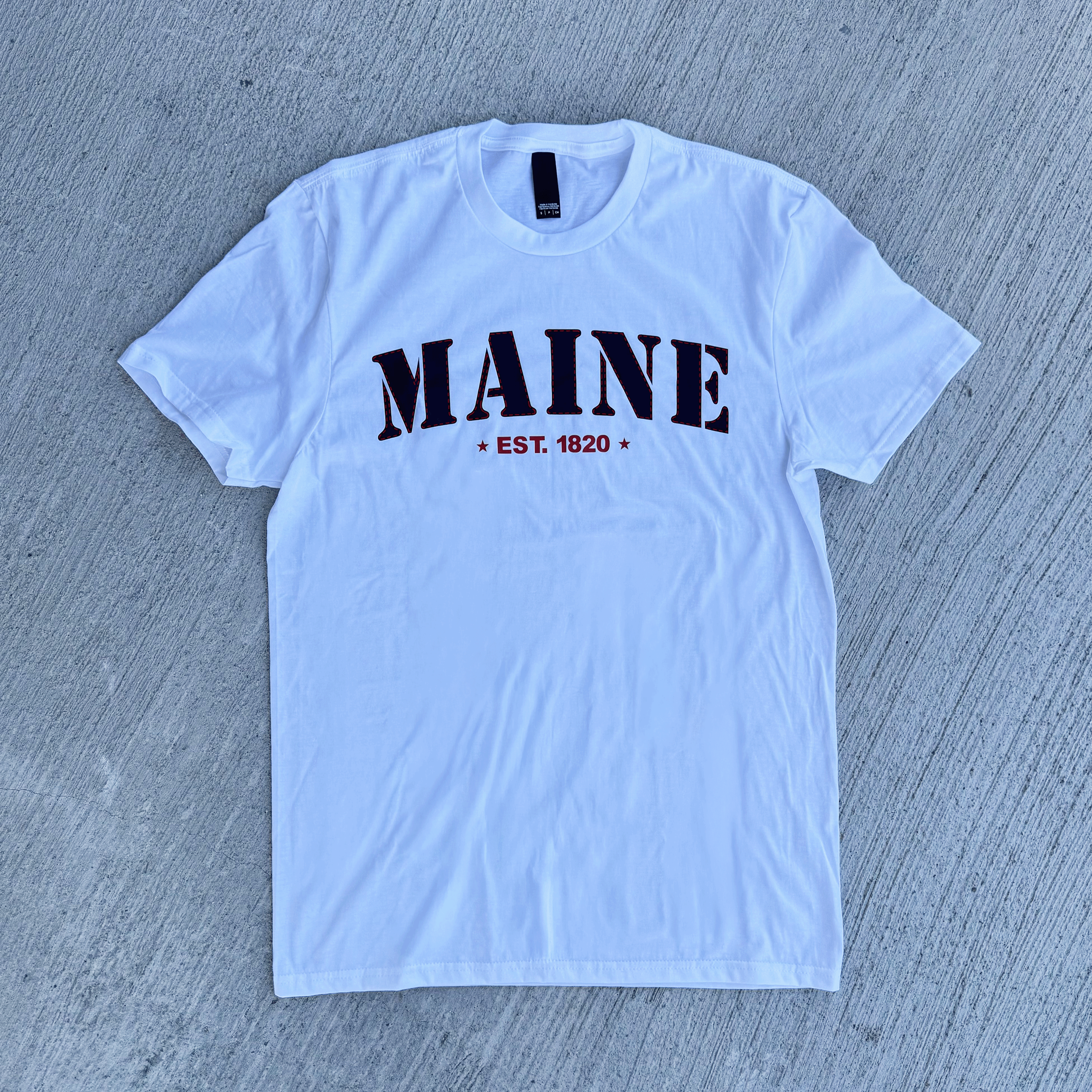 White t-shirt with 'MAINE EST. 1820' text on a gray textured background