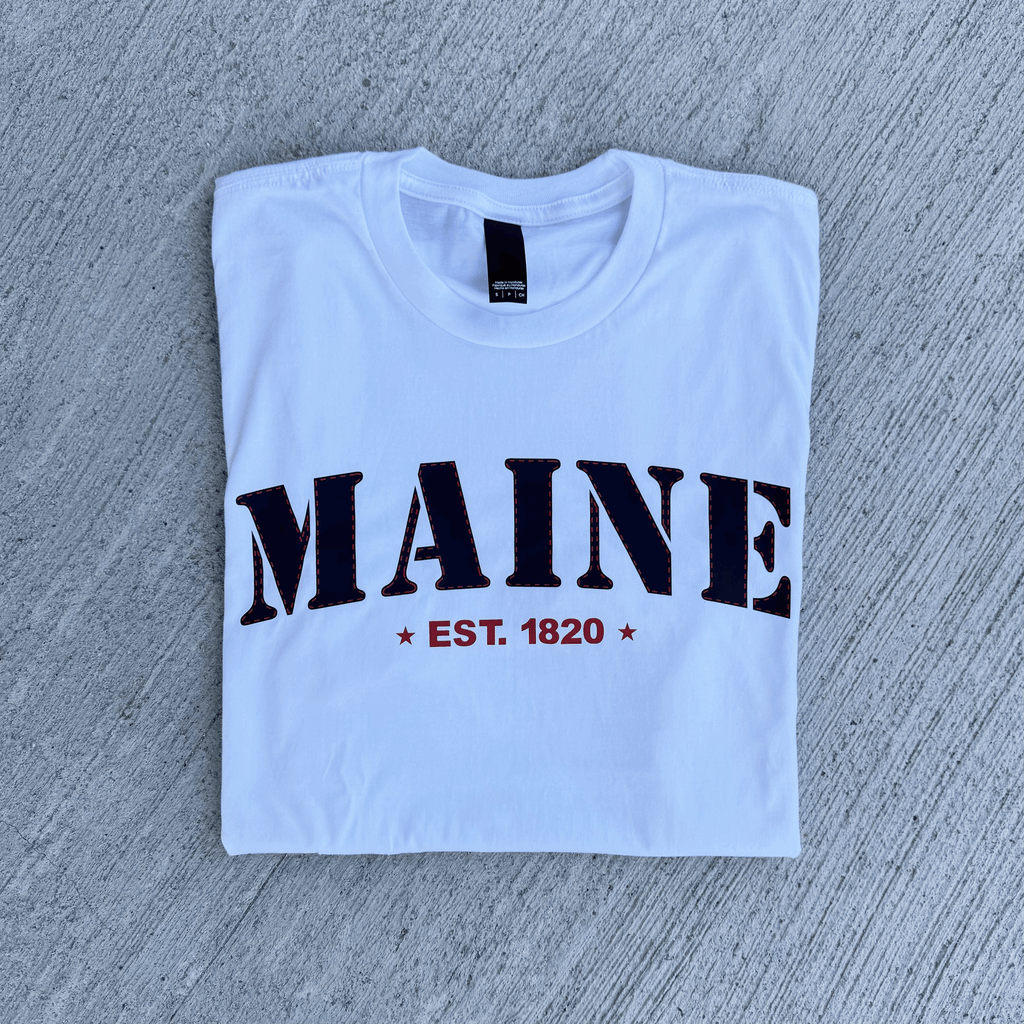 White t-shirt with 'MAINE EST. 1820' text on a gray surface