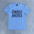 Light blue t-shirt with 'America the Beautiful' design on a gray surface