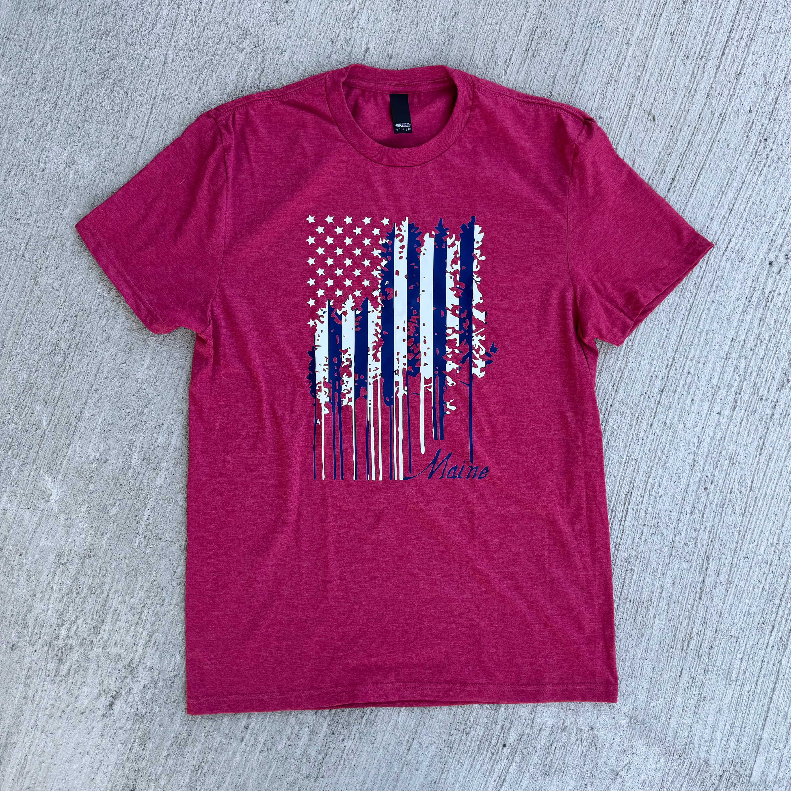 Heather red t-shirt with a graphic design on a gray surface